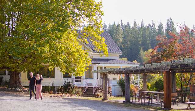 A landscape of a home and an outdoor dining table.