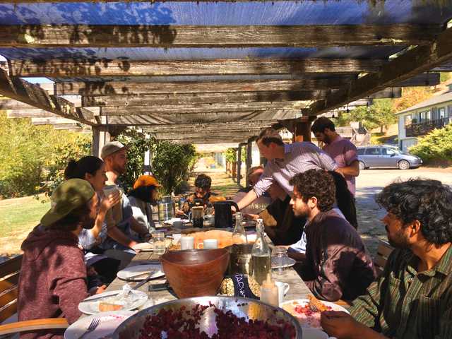 a group of people gathered around a outdoor dining table