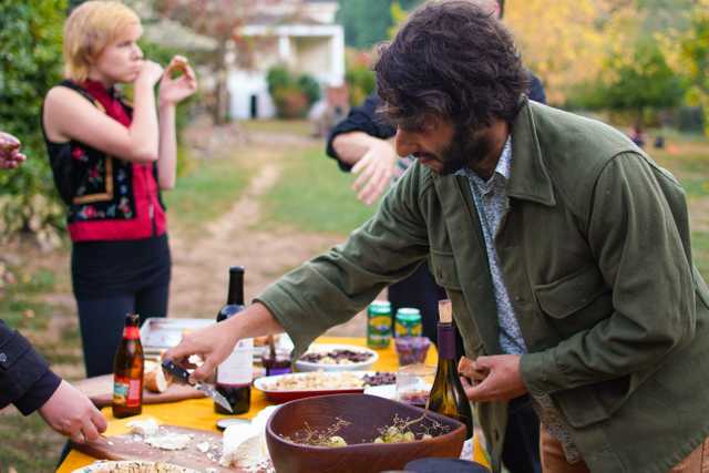 A person picking up a utensil to try some cheese.